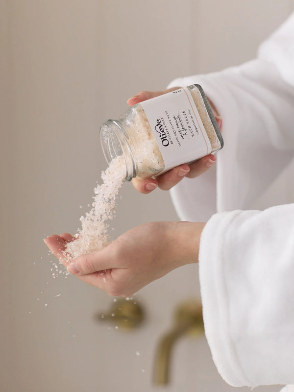 Person pouring Olieve & Olie Bath Salts into their hands. Made with a soothing blend of mineral-rich salts and botanical ingredients, this luxurious bath soak helps relax the body, soften the skin and create a calming spa-like bathing ritual