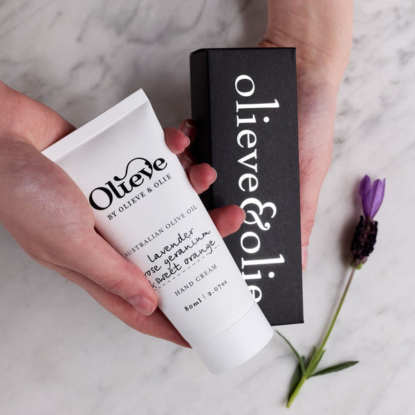 Olieve & Olie Lavender, Rose Geranium & Sweet Orange Hand Cream in a recyclable white sugarcane tube displayed in an elegant lifestyle setting. Handcrafted with Australian olive oil, cocoa butter and beeswax, this nourishing hand cream helps keep hands soft, hydrated and beautifully cared for