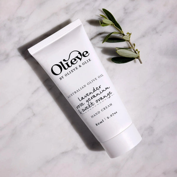 Olieve & Olie Lavender, Rose Geranium & Sweet Orange Hand Cream in a recyclable white sugarcane tube displayed on a marble bench. Handcrafted with Australian olive oil, cocoa butter and beeswax, this rich hand cream deeply nourishes dry hands, leaving them soft, smooth and delicately scented