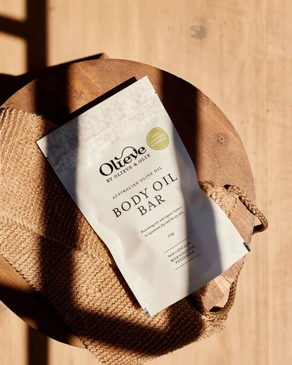 Olieve & Olie Lime, Clary Sage & Lavender Body Oil Bar displayed on a wooden stool. This handcrafted solid body moisturiser is made with Australian olive oil, cocoa butter and beeswax to deeply nourish and soften the skin